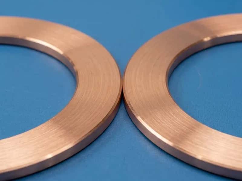 Two OFHC copper sealing rings with turned faces on a blue inspection surface