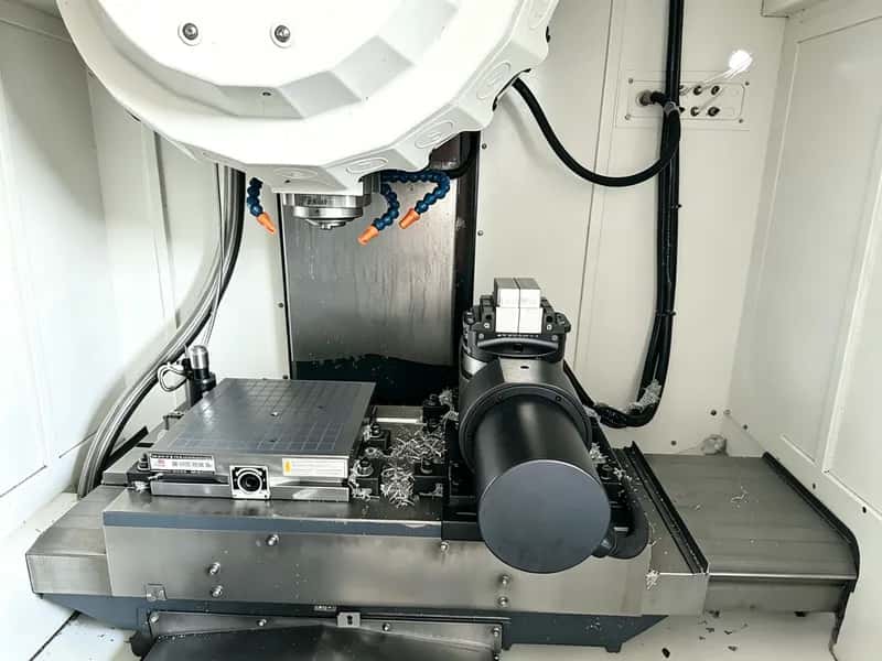 Five-axis CNC machining center worktable and spindle inside an enclosed cell