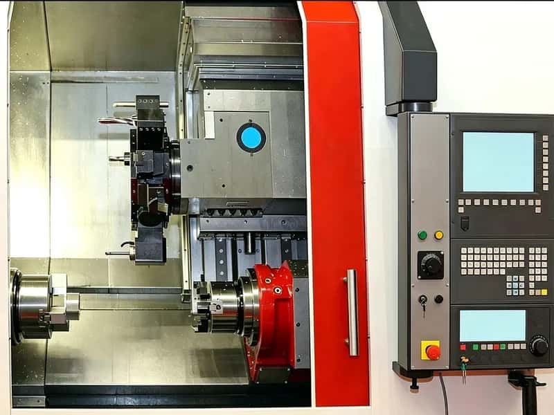 Turn-mill machine interior with workpiece, turret tooling, and dual operator screens