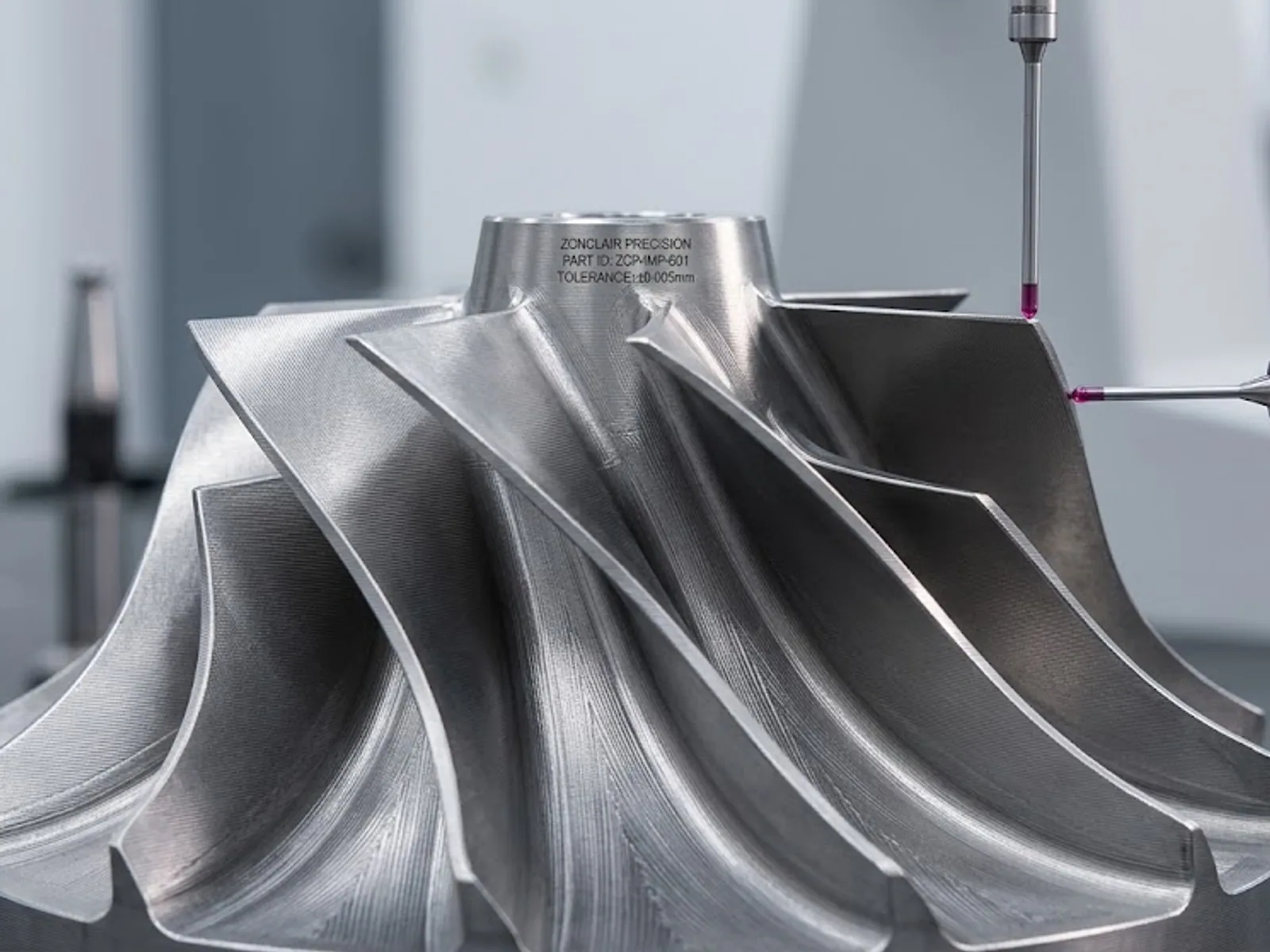 CMM probe measuring a metal impeller with laser-marked part identification on the hub